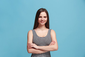 Image showing The happy woman standing and smiling against blue background.