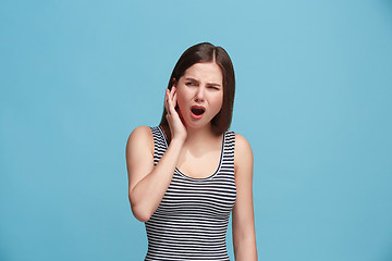 Image showing The Ear ache. The sad woman with headache or pain on a blue studio background.