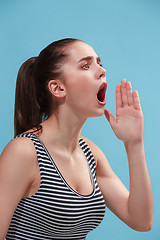 Image showing The young woman is calling on the blue background.