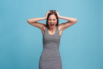 Image showing The young emotional angry woman screaming on blue studio background