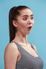 Image showing The young woman is looking surprising on the blue background.