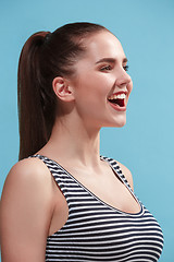 Image showing The happy woman standing and smiling against blue background.