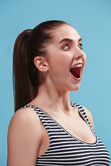 Image showing The happy woman standing and smiling against blue background.