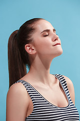 Image showing The young woman is looking satisfy on the blue background.