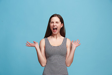 Image showing The young emotional angry woman screaming on blue studio background