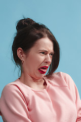 Image showing Young woman with disgusted expression repulsing something, isolated on the blue