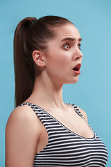 Image showing The young woman is looking surprising on the blue background.