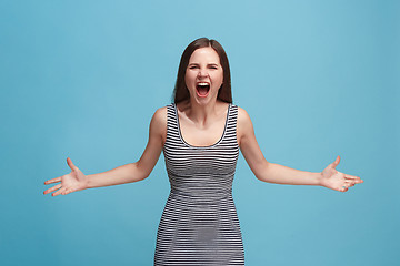 Image showing The young emotional angry woman screaming on blue studio background