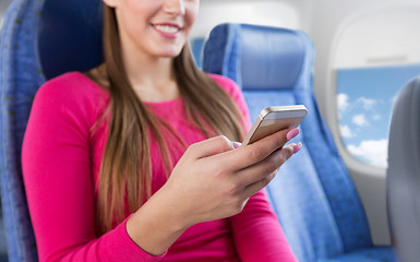 Image showing close up of woman sitting in plane with smartphone