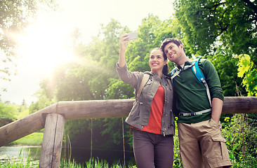 Image showing couple with backpacks taking selfie by smartphone