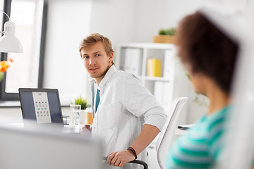 Image showing happy creative workers with laptops at office