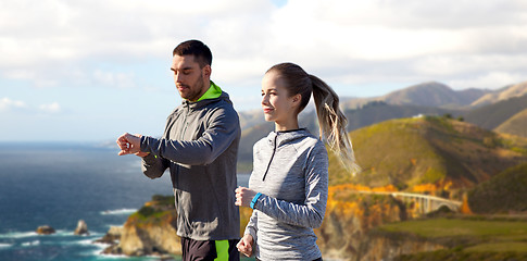 Image showing couple with fitness trackers running outdoors