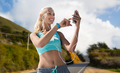 Image showing woman with smartphone and earphones doing sports