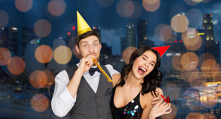 Image showing happy couple with party blowers having fun