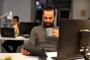 Image showing man with tablet pc drinking coffee at office