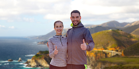 Image showing smiling couple in sport clothes showing thumbs up