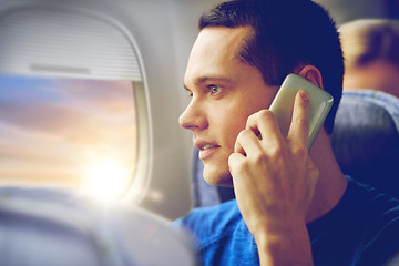 Image showing young man calling on smartphone in plane