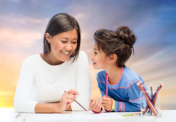 Image showing happy mother and daughter drawing over evening sky