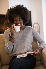 Image showing black woman reading book  in front of fireplace