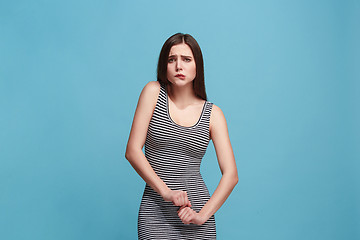 Image showing The awkward woman standing and looking at camera against blue background.