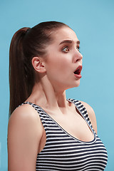 Image showing The young woman is looking surprising on the blue background.