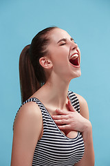 Image showing The happy woman standing and smiling against blue background.