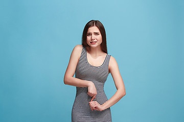 Image showing The awkward woman standing and looking at camera against blue background.