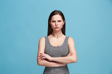 Image showing The serious woman standing and looking at camera against blue background.