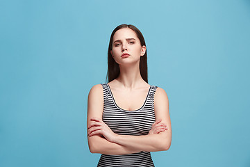 Image showing The serious woman standing and looking at camera against blue background.