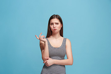 Image showing Let me think. Doubtful pensive woman with thoughtful expression making choice against blue background