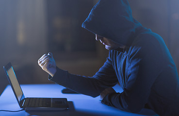 Image showing hacker showing fist to laptop in dark room
