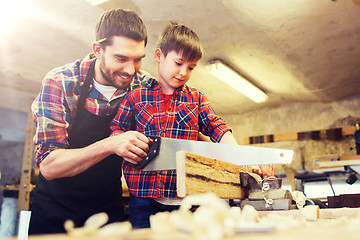 Image showing father and son with saw working at workshop