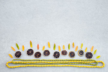 Image showing Autumn ornament made of leaves, dried lemon slices and necklaces