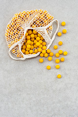 Image showing Yellow plums in a mesh bag on concrete background