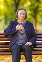 Image showing Puzzled aging woman having heart attack outdoors