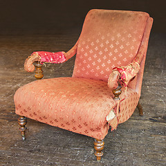 Image showing Old tattered red armchair on a wooden parquet