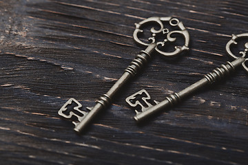 Image showing Two vintage bronze keys on a wooden table