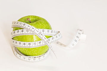 Image showing Measuring tape wrapped around a green apple.