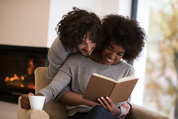 Image showing multiethnic couple hugging in front of fireplace