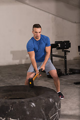 Image showing man workout with hammer and tractor tire