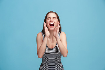 Image showing Isolated on blue young casual woman shouting at studio