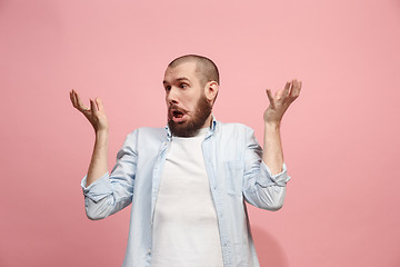 Image showing Beautiful male half-length portrait isolated on pink studio backgroud. The young emotional surprised man