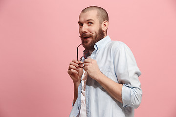 Image showing The young man whispering a secret behind her hand over pink background