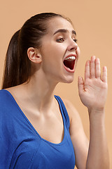 Image showing The young woman is calling on the pastel background.