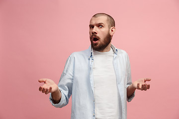 Image showing Beautiful male half-length portrait isolated on pink studio backgroud. The young emotional surprised man