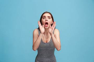 Image showing Isolated on blue young casual woman shouting at studio