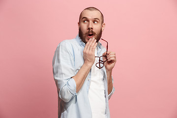 Image showing The young man whispering a secret behind her hand over pink background