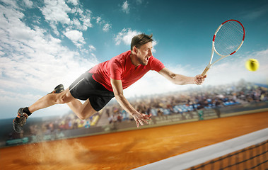 Image showing The one jumping player, caucasian fit man, playing tennis on the earthen court with spectators