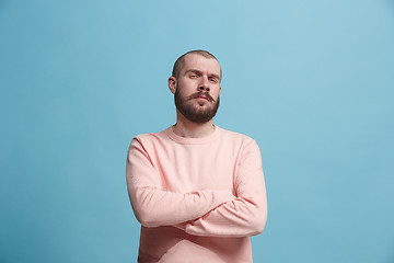 Image showing The serious businessman standing and looking at camera against blue background.