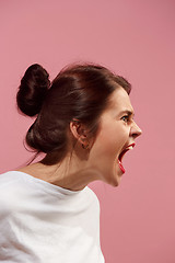 Image showing The young emotional angry woman screaming on pink studio background